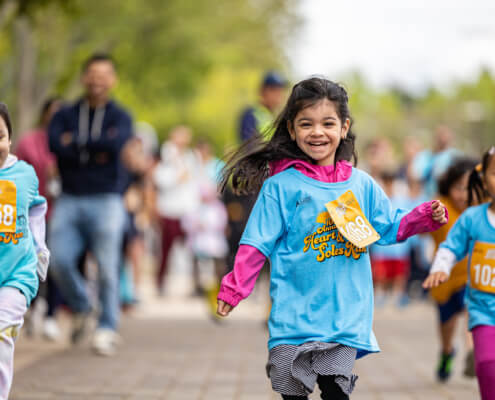 A young girl runs exuberantly in the Kids Run at Heart & Soles